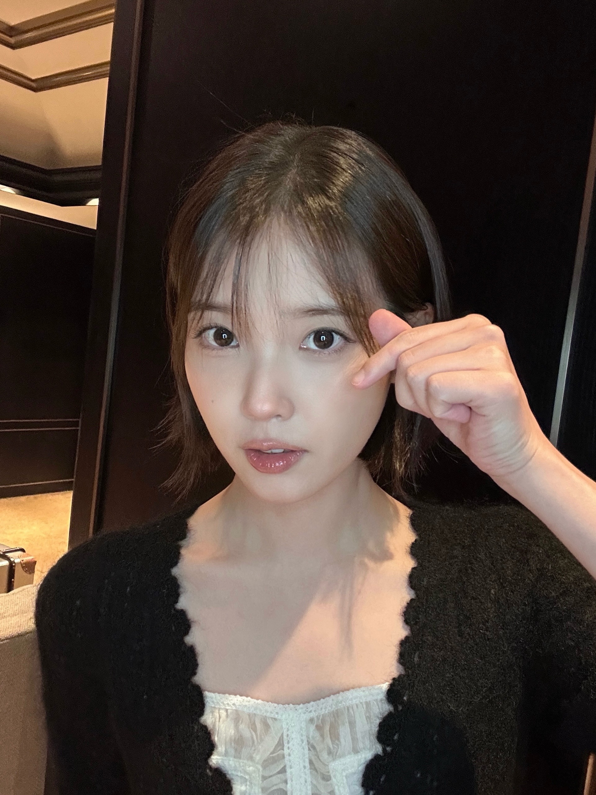 검은 겉옷 차림의 인물이 눈 옆으로 손을 올린 근접 사진