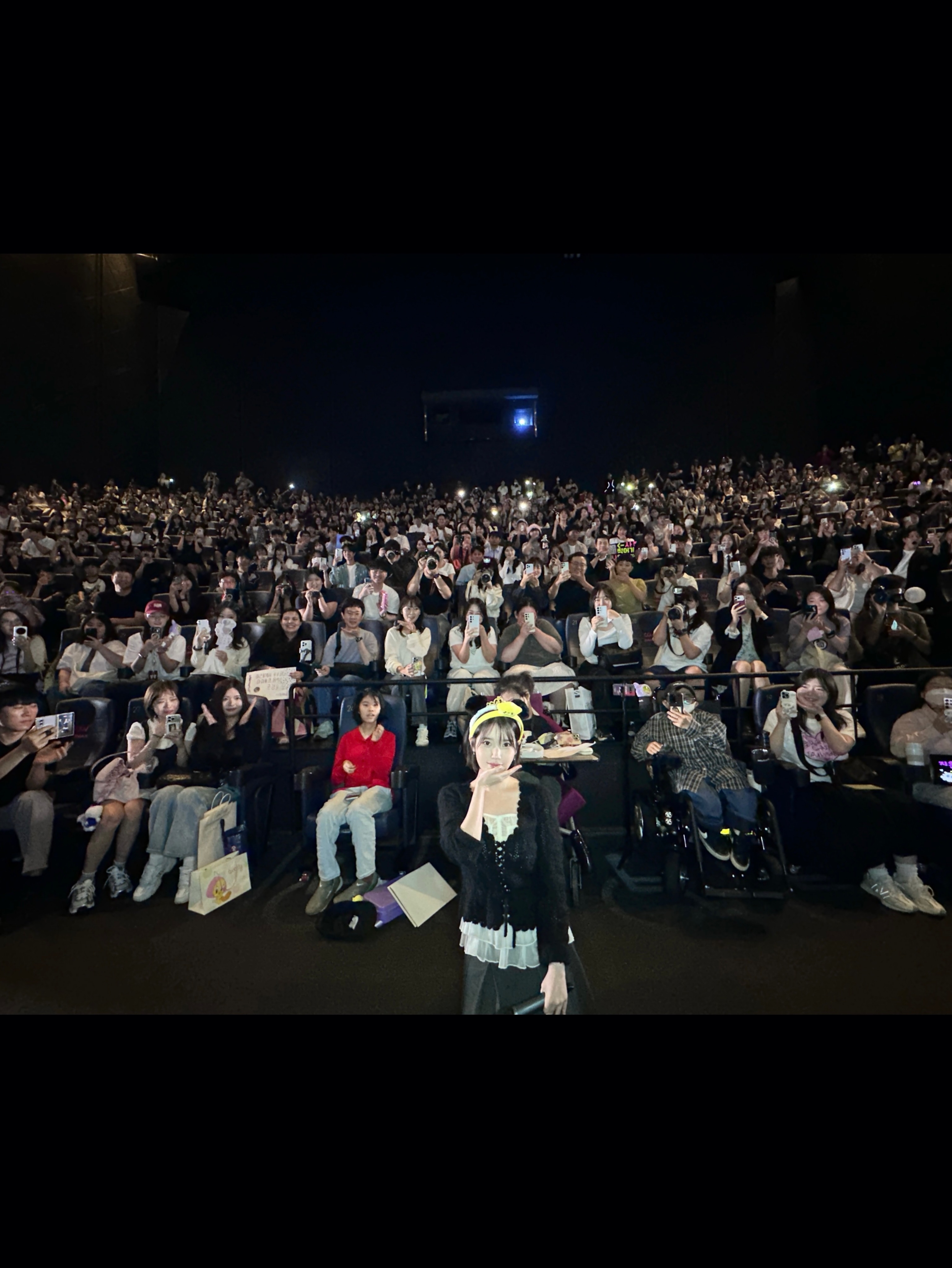 객석을 향한 정면 구도에서 앞쪽 인물과 관객들이 함께 보이는 사진