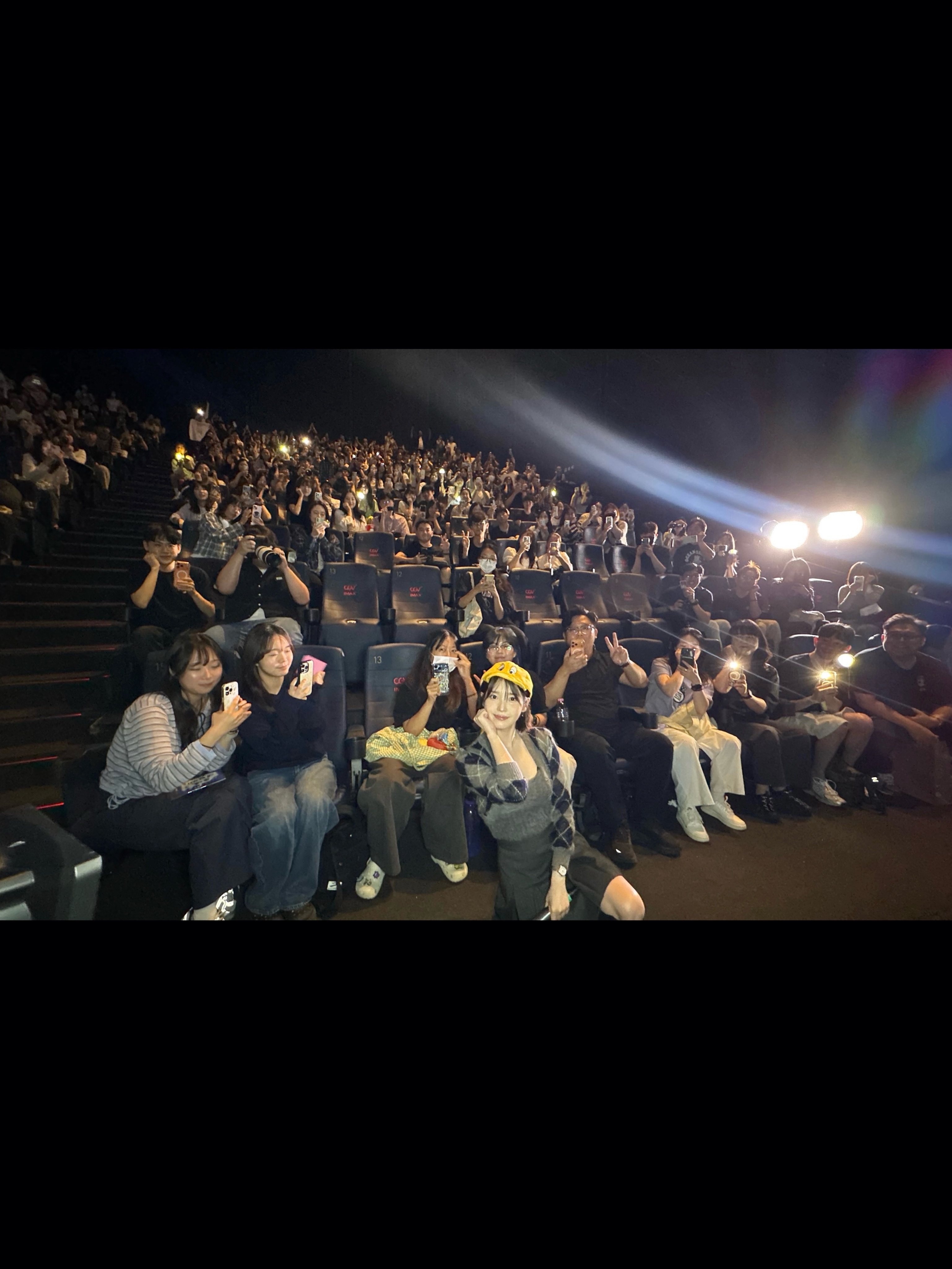 오른쪽에서 비치는 조명과 객석 앞의 인물, 관객들이 보이는 사진